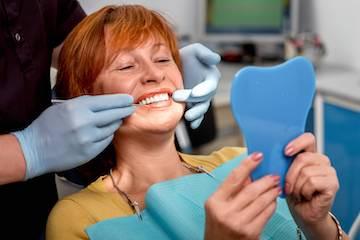 woman showing off smile in mirror after cosmetic dentistry treatments