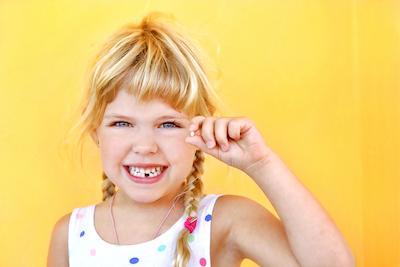 Young girl showing off baby tooth she lost