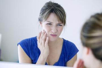 woman holding jaw from TMJ pain
