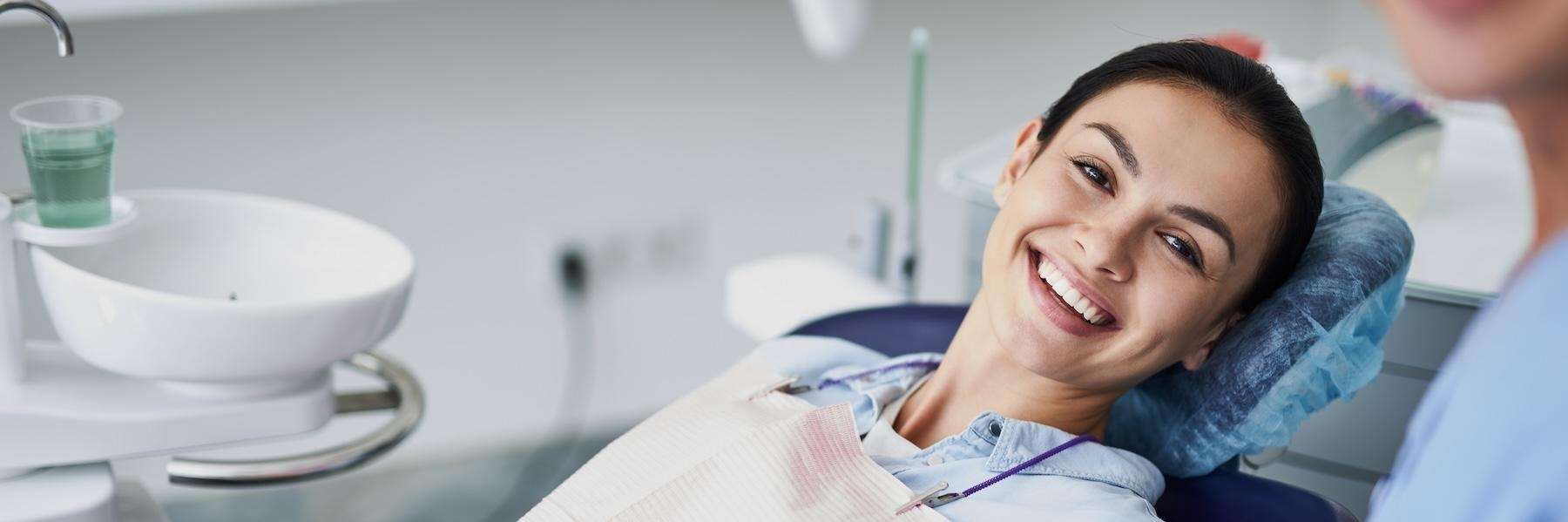 woman sitting in a dental chair while smiling