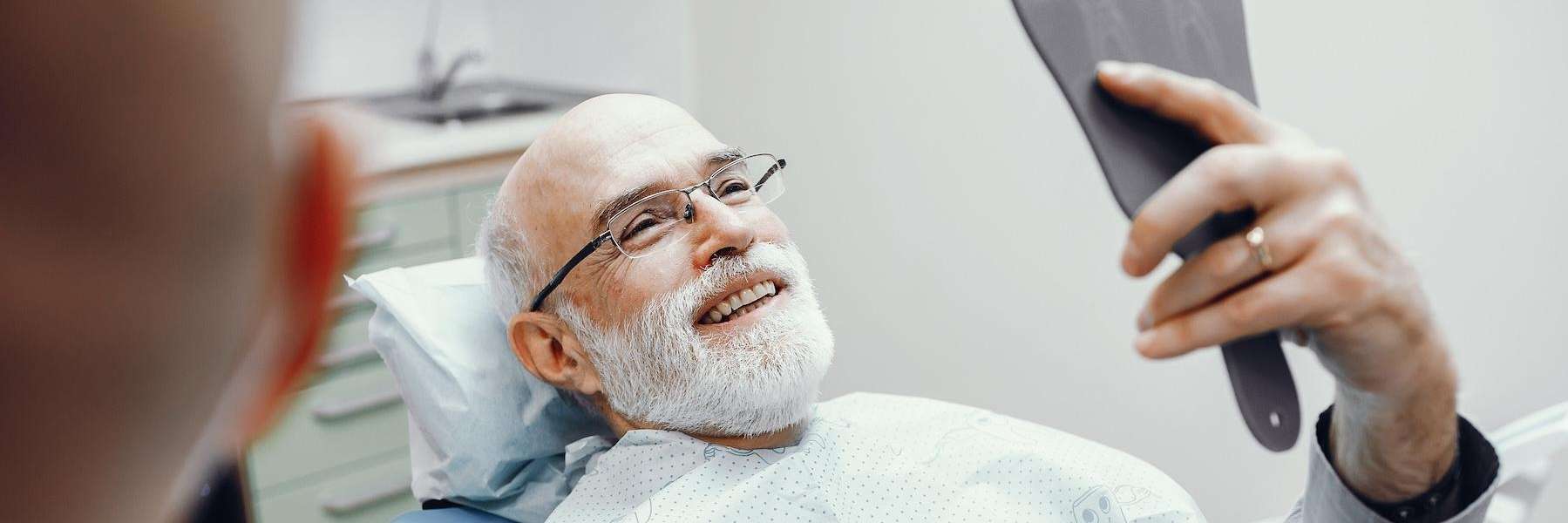 man holding a mirror after successful dental implants