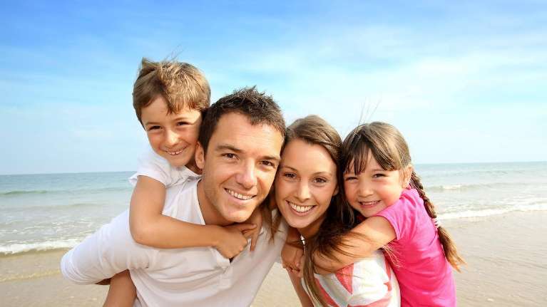mom, dad, daughter, and son smiling on the beach