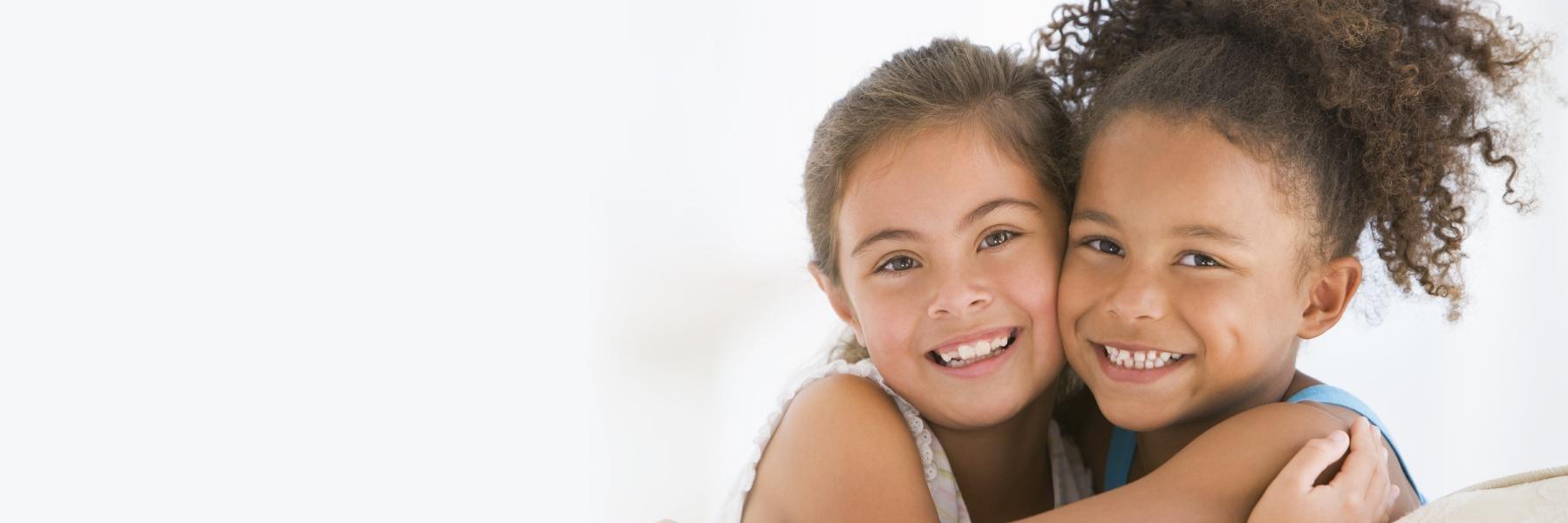 two young girls hugging and smiling
